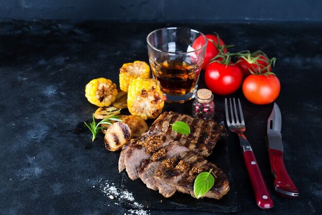 Steak et légumes grillés, pommes de terre au four et salade verte à la noirceur