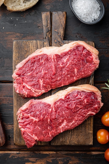 Steak de New York, viande de boeuf crue, sur table en bois foncé, vue du dessus