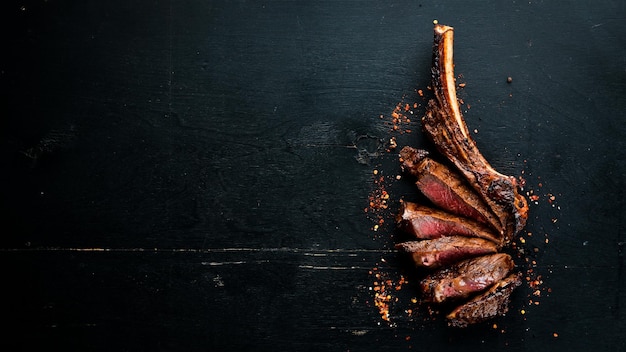 Steak sur l'os steak de tomahawk Sur un fond en bois noir Vue de dessus Espace de copie gratuit