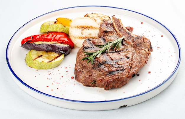 Steak d'os de veau aux légumes grillés sur fond blanc