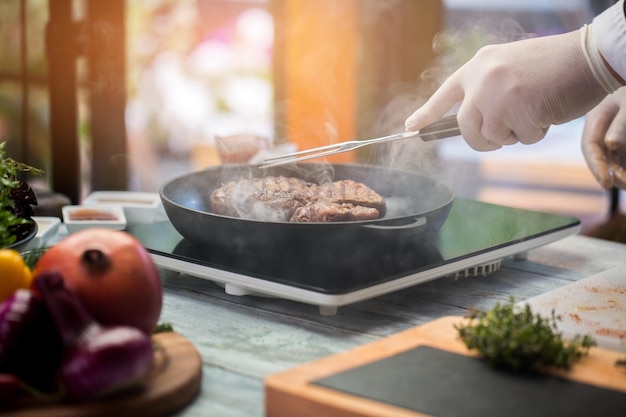 Steak à la poêle. La main tient une fourchette à viande. Le chef du café prépare du veau. Un arôme si savoureux.