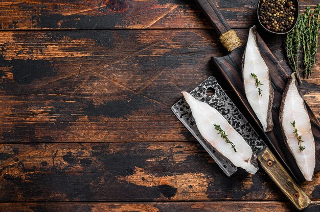 Steak de poisson de flétan frais cru sur une planche à découper en bois.