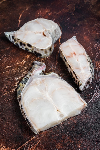 Steak de poisson loup de l'atlantique cru. Fond sombre. Vue de dessus.