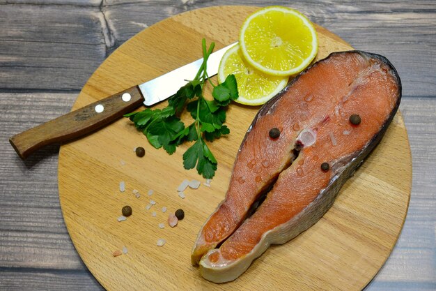 steak de poisson rouge avec du sel, des tranches de citron et un couteau sur une planche à découper, gros plan