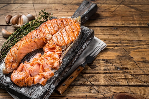 Steak de poisson à la truite saumonée grillée sur une planche de bois avec des herbes Fond en bois Vue de dessus Espace de copie