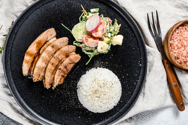 Steak de poitrine de dinde, volaille, accompagnement de riz et salade. Fond gris. Vue de dessus