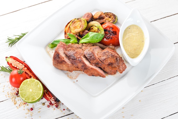 Steak de porc aux légumes grillés sur une assiette Sur un fond en bois Vue de dessus Espace de copie