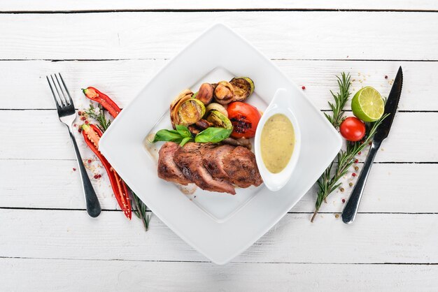 Steak de porc aux légumes grillés sur une assiette Sur un fond en bois Vue de dessus Espace de copie