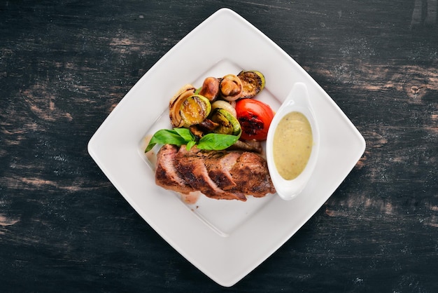 Steak de porc aux légumes grillés sur une assiette Sur un fond en bois Vue de dessus Espace de copie