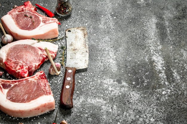 Steak de porc cru avec un brin de romarin et d'épices sur table rustique.