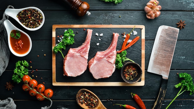 Steak de porc cru sur l'os Sur une planche de pierre avec des épices et des herbes Vue de dessus Espace libre pour votre texte