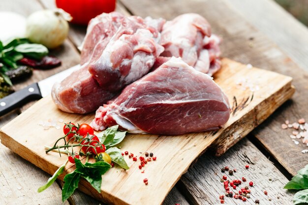 Steak de porc cru sur l'os sur une table en bois Cuisson de la viande