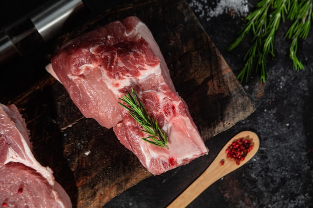 Steak de porc cru sur l'os sur une table en bois. Cuisson de la viande