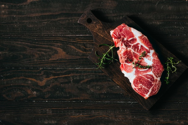 Steak de porc cru sur une planche de bois