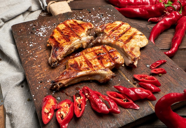 Steak de porc frit sur la côte se trouve sur une planche de bois brune vintage