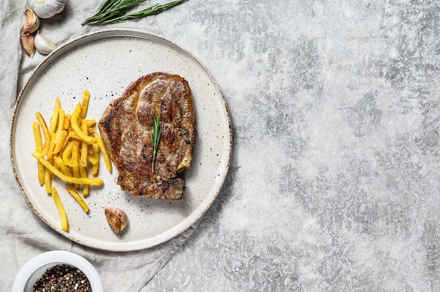 Steak de porc grillé sur os avec frites.