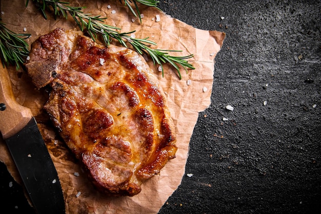 Steak de porc grillé sur papier avec du romarin