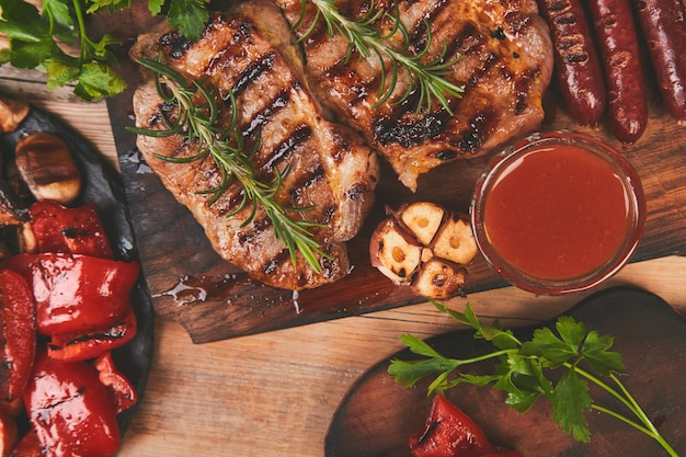 Steak de porc grillé sur une planche à découper en bois avec une variété de légumes grillés