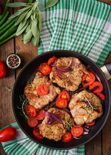 Steak de porc juteux au romarin et aux tomates sur le plat