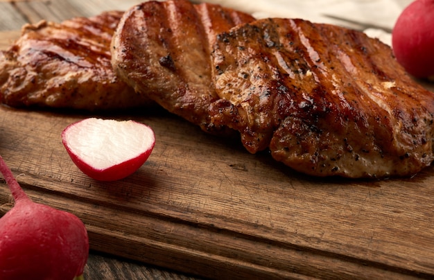 Steak de porc juteux frit sur une planche de bois, viande grillée