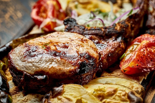 Steak de porc à l'os grillé avec des légumes sur une planche de bois Gros plan