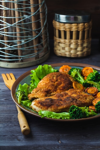 Steak de poulet dans la chapelure avec des légumes sur une assiette