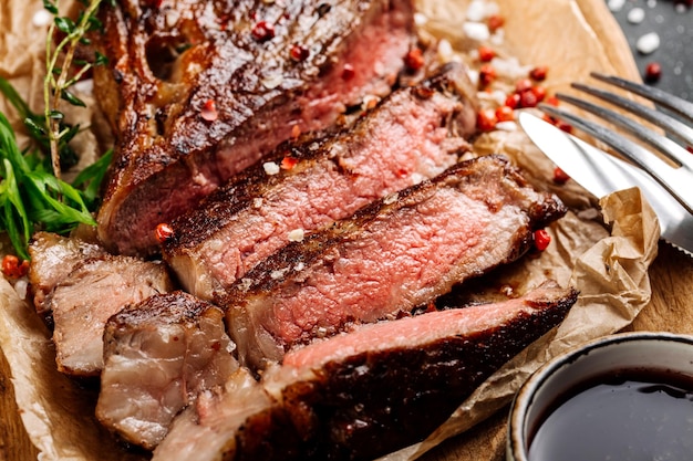 Steak de rumsteck de bœuf en marbre mi-saignant avec sauce sur plaque de bois gros plan Mise au point sélective