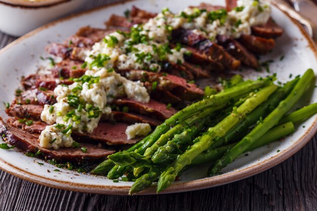 Steak à la sauce au fromage bleu servi avec des asperges.