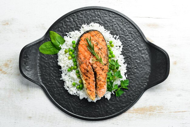 Steak de saumon cuit au four avec du riz et des légumes sur une plaque en pierre noire Fruits de mer Vue de dessus Espace libre pour votre texte