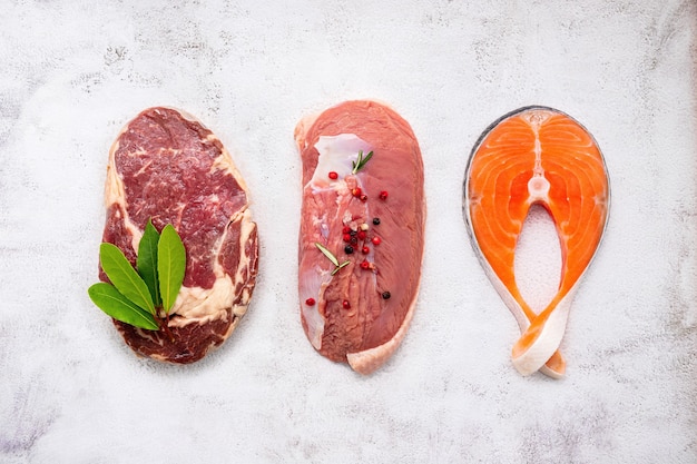 Steak, saumon et faux-filet sur fond de marbre blanc