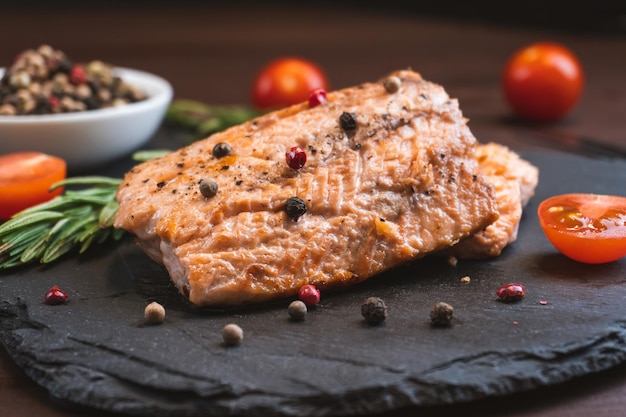 Steak de saumon de viande de poisson rouge grillé avec tomate romarin et épices sur fond de pierre noire