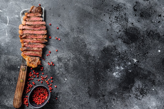 Steak de surlonge grillé sur un couperet. Le milieu de cuisson. Fond noir