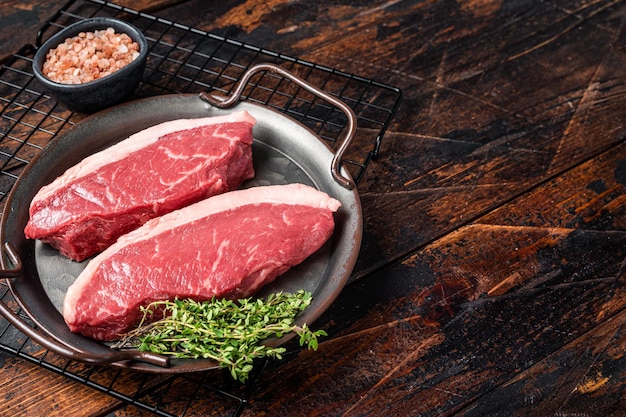 Steak de surlonge haut cru rumsteck steak de viande de boeuf sur le plateau de la cuisine avec des épices fond en bois vue de dessus espace de copie