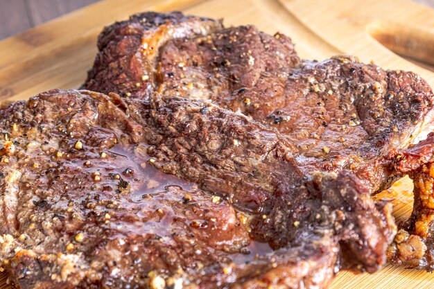 Steak de surlonge rôti coupé en steaks sur une planche de bois sur une table en bois