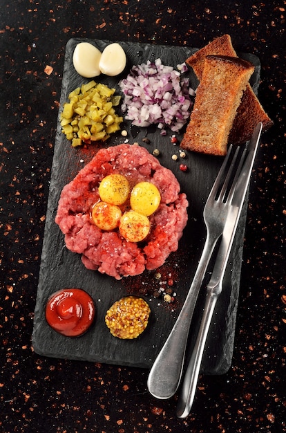 Steak tartare sur plaque de pierre noire sur table en marbre