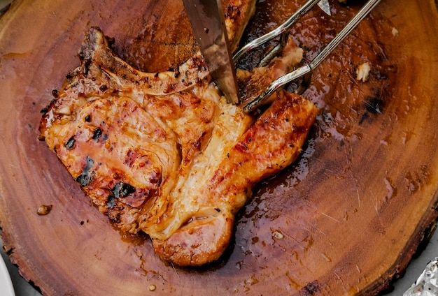 Steak de Tbone grillé sur un four chaud et fumé saupoudré de poivre et sel et de romarin séché