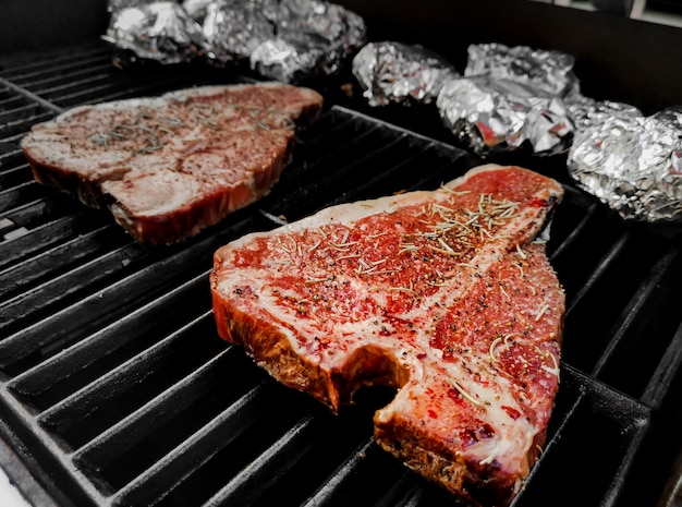 Steak de Tbone grillé sur un four chaud et fumé saupoudré de poivre et de sel