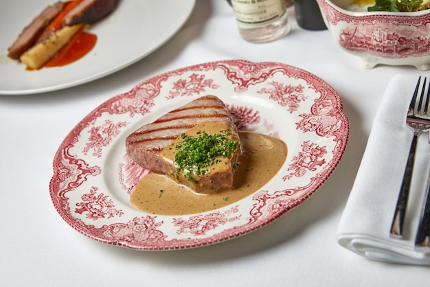 Photo steak de thon aux légumes verts sous une délicieuse sauce sur une belle assiette