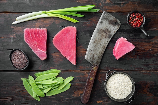 Steak de thon cru, filet de thon rouge frais avec ingrédients, pois verts, sésame et épices, et vieux couteau couperet de boucher, sur la vieille table en bois sombre