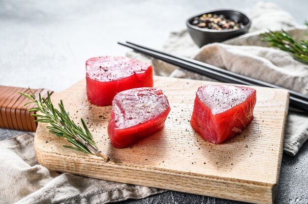 Steak de thon frais sur une planche à découper. Fond gris. Vue de dessus