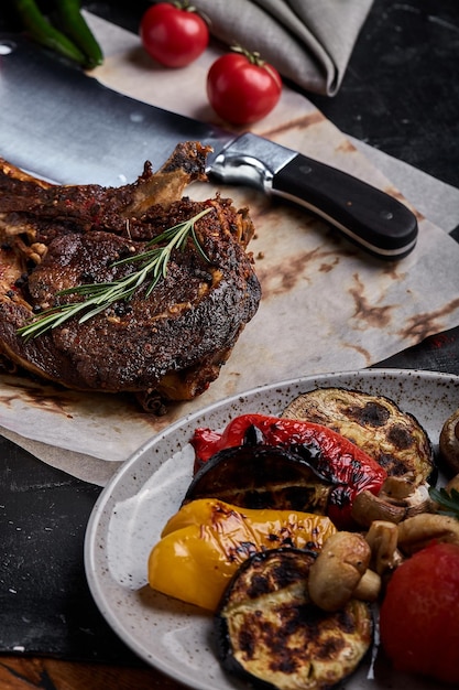 Steak de tomahawk avec légumes et couteau sur la table Viande grillée avec légumes grillés et légumes frais sur la table