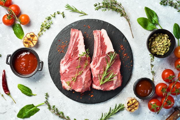 Steak de veau cru sur l'os sur une plaque d'ardoise noire sur un fond de pierre