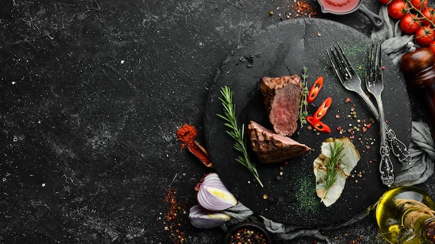 Steak de veau cuit au four avec des épices sur une plaque en pierre noire Steak au poivre Vue de dessus espace libre pour votre texte Style rustique