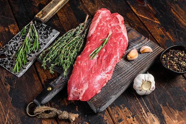 Steak de viande de boeuf de flanc cru sur une planche à découper avec couperet.