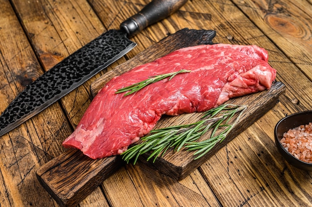 Steak de viande de boeuf de flanc cru sur une planche à découper avec un couteau