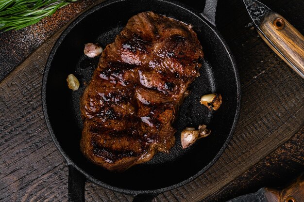 Photo steak de viande de boeuf grillé avec sauce au poivre sur la vieille vue de dessus de fond de table rustique sombre mise à plat