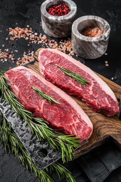 Steak de viande de boeuf rumsteck cru ou haut de surlonge sur planche de boucher Fond noir Vue de dessus