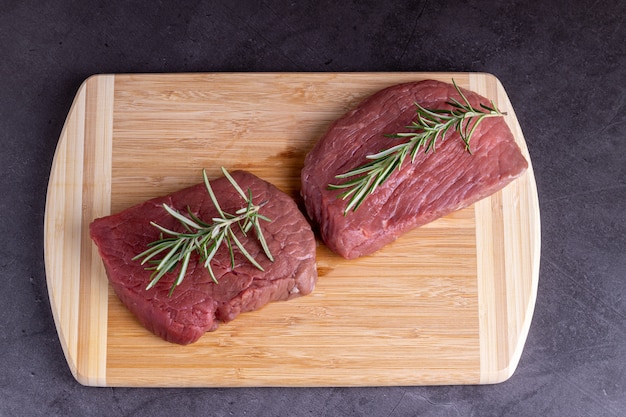 Photo steak de viande de boeuf en tranches crues fraîches sur une planche de bois