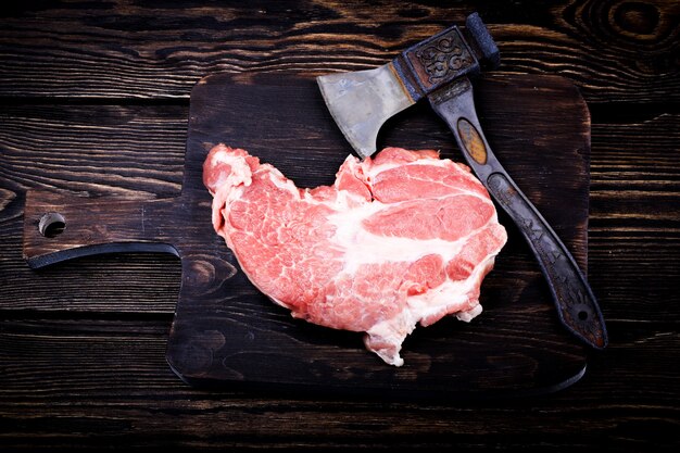 Steak de viande crue sur une hache de planche à découper