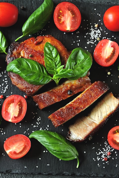 Steak de viande fraîche appétissante sur un tableau avec tomates et basilic.